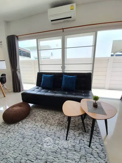 Modern living room with stylish sofa and coffee table, bright natural light through large windows.
