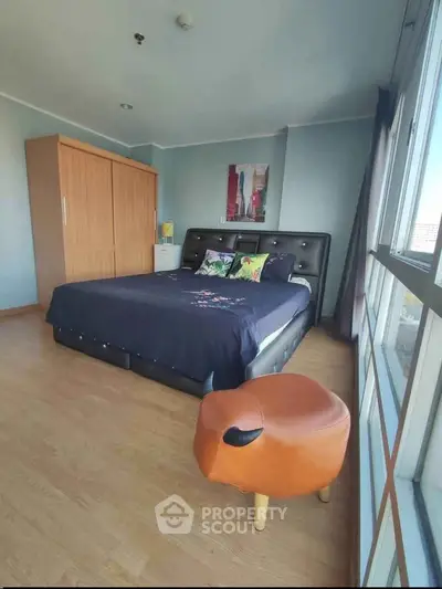 Spacious bedroom with large window and modern decor in a stylish apartment.