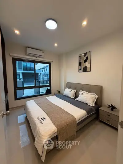 Modern bedroom with stylish decor and large window offering natural light.