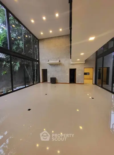 Spacious modern living room with high ceilings and large windows overlooking garden.