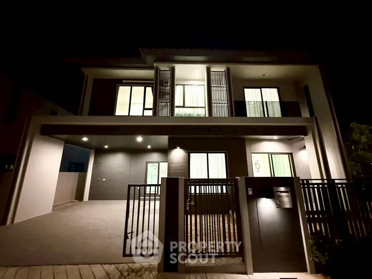 Modern two-story house with sleek design and illuminated facade at night.
