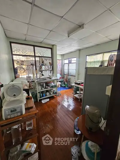 Cozy kitchen with wooden floors and ample natural light, featuring modern appliances and open shelving.