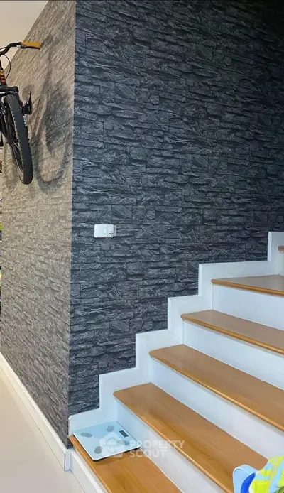 Stylish modern staircase with stone accent wall and wooden steps