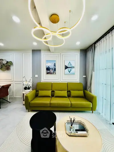 Modern living room with stylish green sofa, elegant lighting, and chic decor in a contemporary apartment.