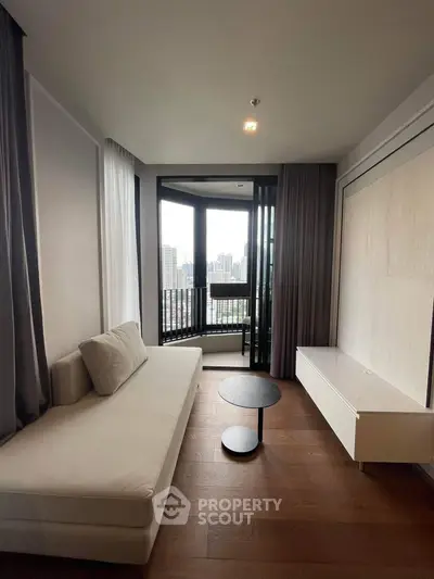 Modern living room with city view, featuring sleek furniture and floor-to-ceiling windows.