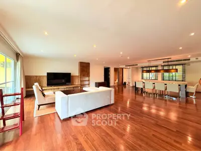 Spacious open-plan living room with elegant wooden flooring and modern furniture.