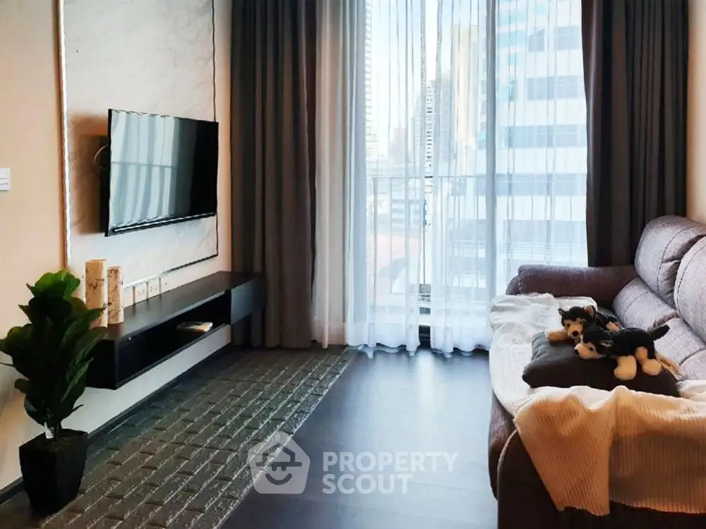 Modern living room with cozy sofa, wall-mounted TV, and city view through large window.