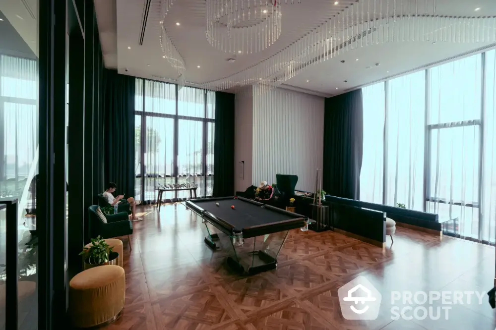 Luxurious living room with pool table and elegant decor, featuring floor-to-ceiling windows and modern lighting.