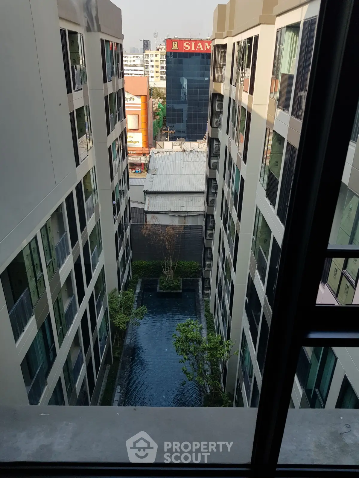 Modern apartment building with central courtyard pool and city view.
