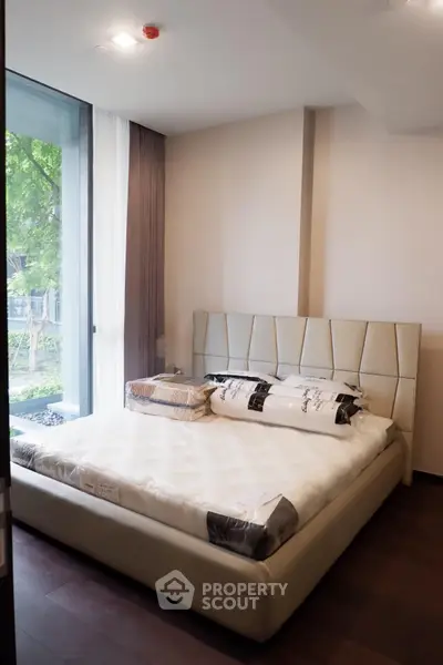 Modern bedroom with large window and stylish bed in a serene setting.