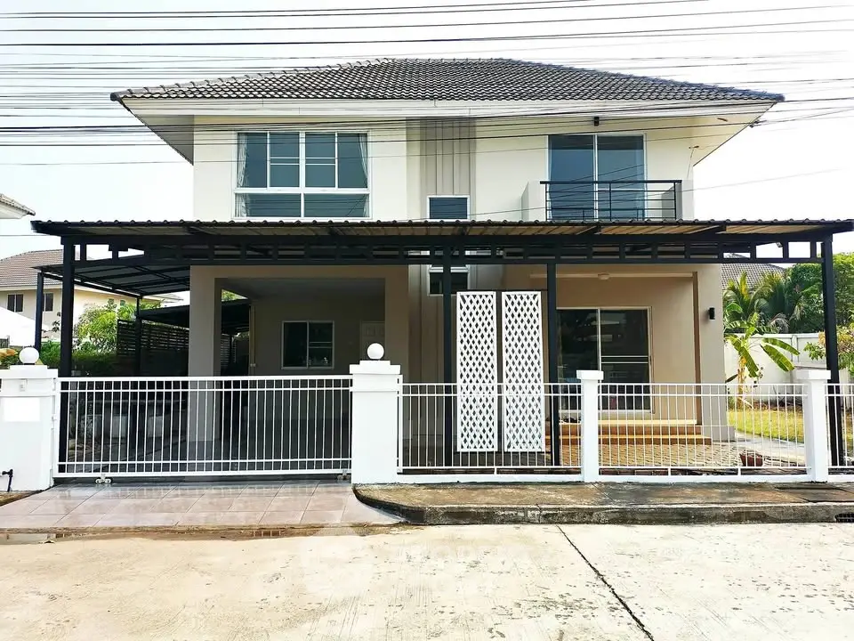 Modern two-story house with spacious balcony and gated entrance in suburban neighborhood.