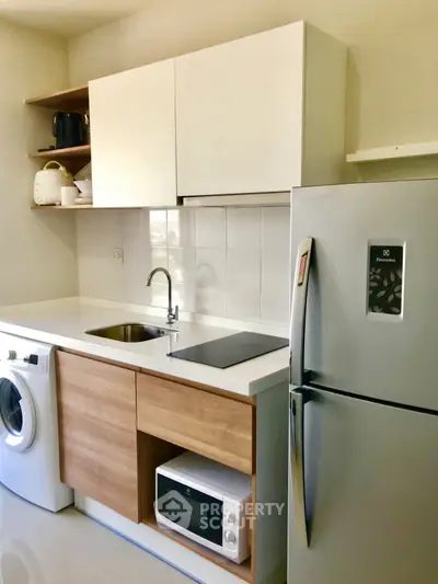 Modern kitchen with sleek appliances, washing machine, and ample storage in a compact layout.
