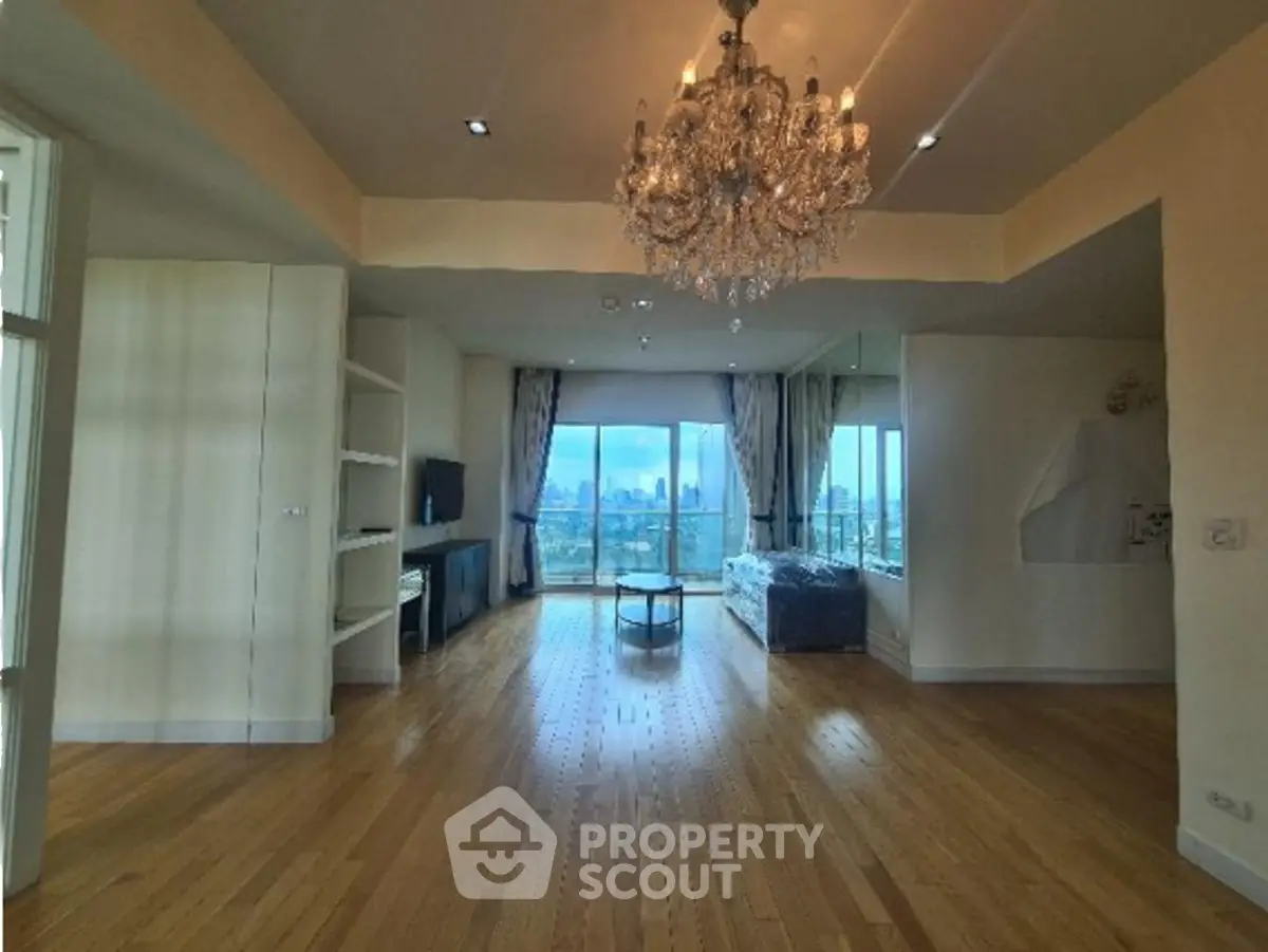 Spacious living room with chandelier and city view, perfect for luxury living.