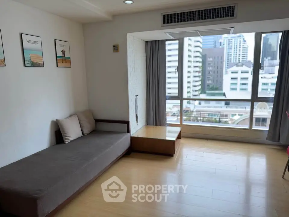 Spacious living room with large window offering city views, modern decor, and cozy seating area.