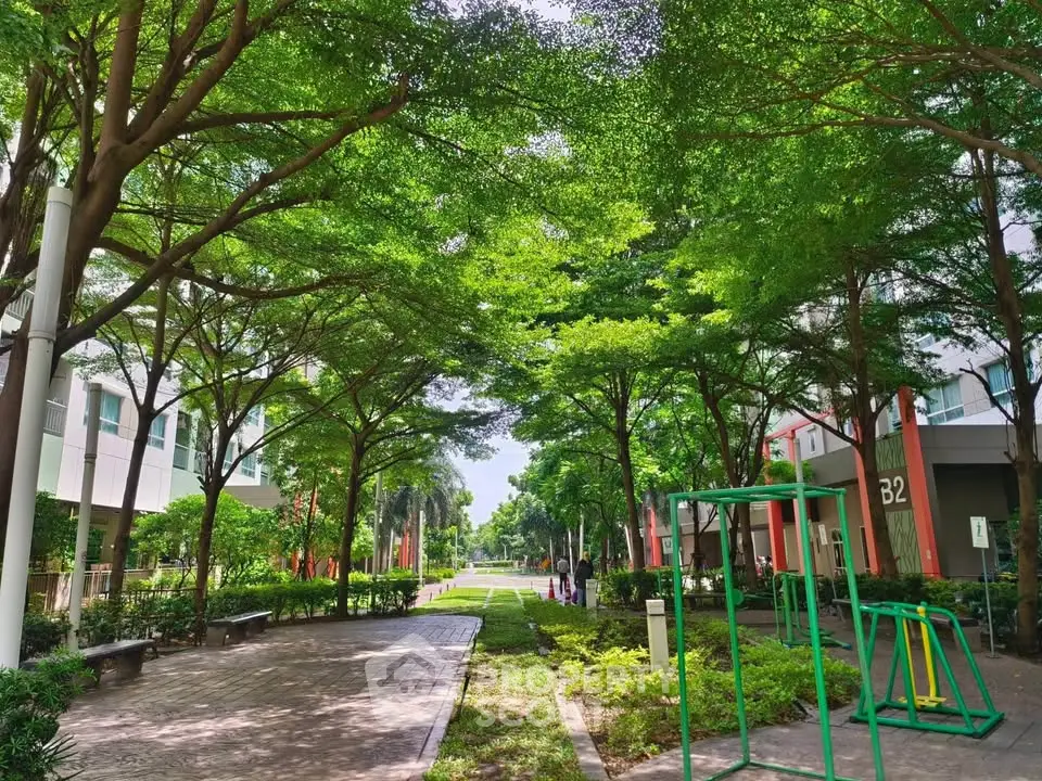 Lush green garden area with pathways and exercise equipment in a modern residential complex.