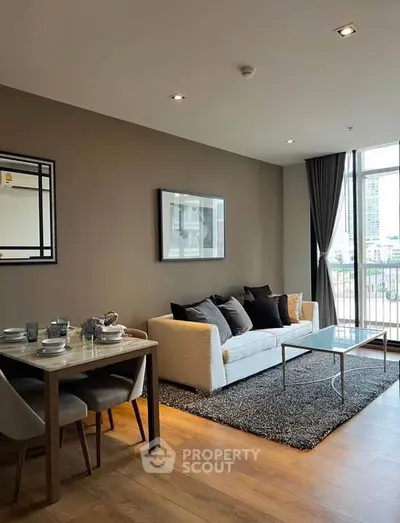 Modern living room with stylish decor and large windows offering city views.