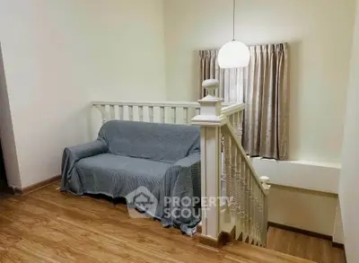 Cozy interior with wooden flooring and a staircase, featuring a comfortable sofa and elegant lighting.