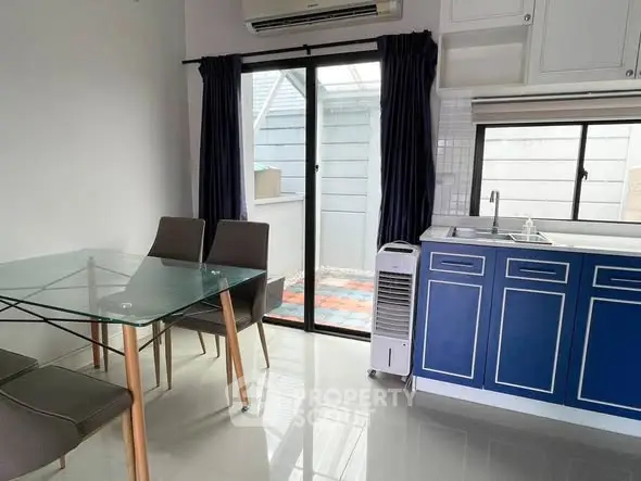 Modern kitchen with blue cabinets and glass dining table in bright interior.