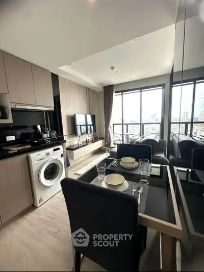 Modern apartment with open kitchen and city view, featuring a washing machine and stylish dining area.