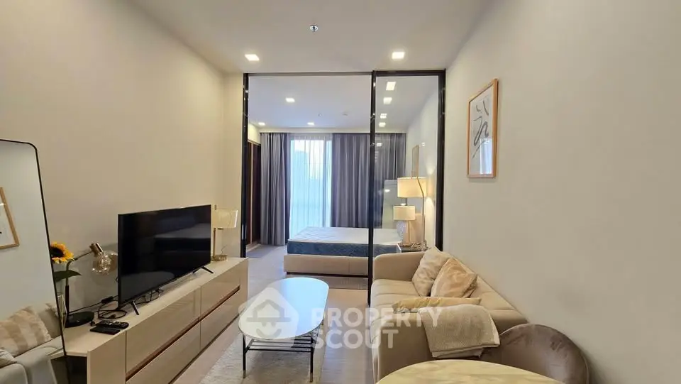 Modern living room with cozy seating and stylish decor leading to a spacious bedroom.