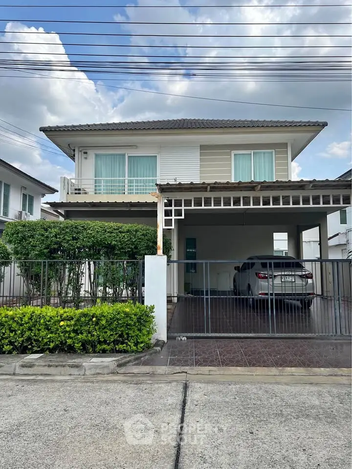 Modern two-story house with carport and lush greenery, perfect for family living.