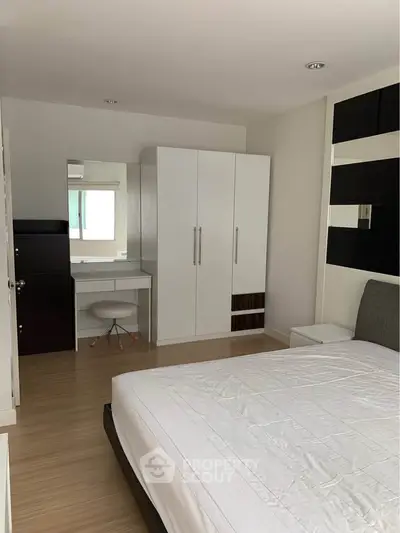 Modern bedroom with sleek furniture and ample storage space, featuring a stylish wardrobe and vanity area.
