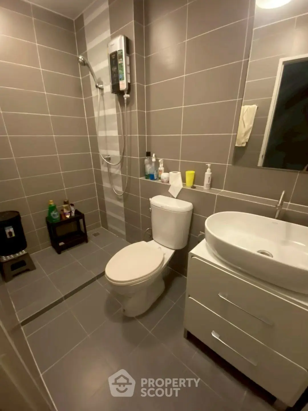 Modern bathroom with sleek fixtures and neutral tiles, featuring a shower and vanity.