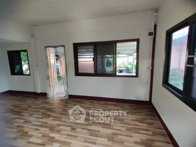 Spacious room with large windows and wooden flooring, ideal for customization.