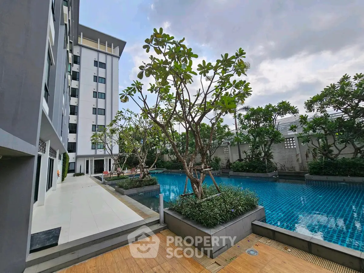 Modern apartment building with lush poolside area and greenery