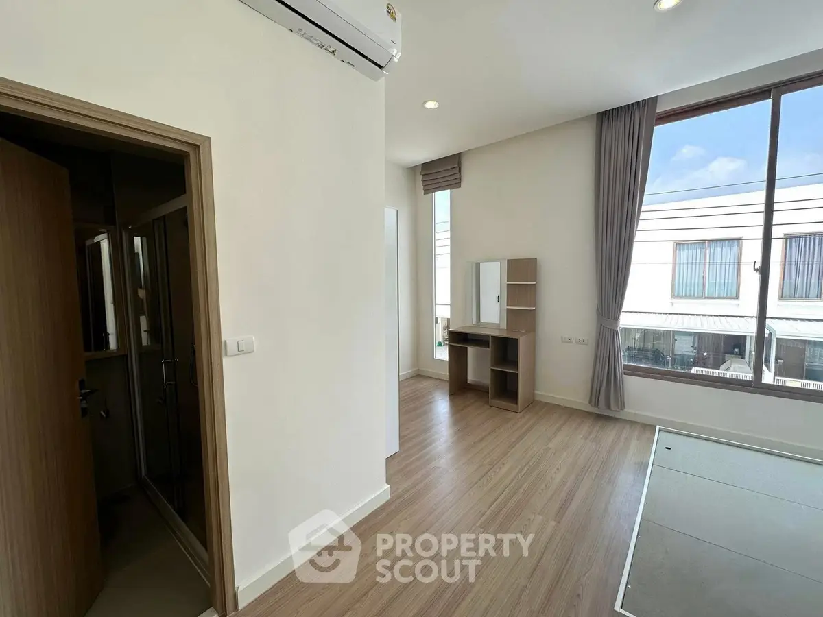Spacious modern room with large window and wooden flooring, perfect for a bright and airy living space.
