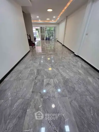 Spacious modern living room with glossy marble flooring and ample natural light.