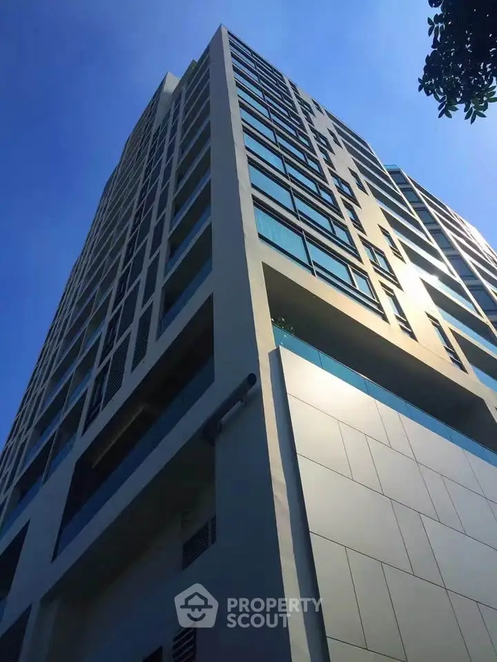 Modern high-rise building with sleek design and large windows under clear blue sky.