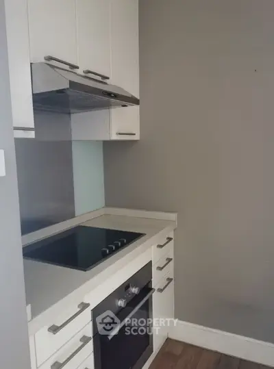 Modern kitchen with sleek cabinetry and built-in oven in a compact layout.