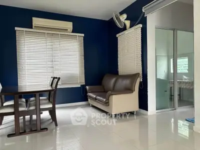 Modern living room with blue accent wall, dining table, and cozy seating area.