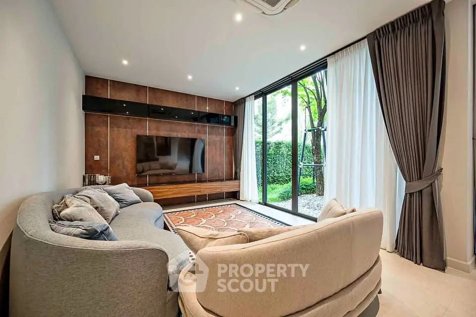 Luxurious living room with modern decor and large glass doors opening to a lush garden view.