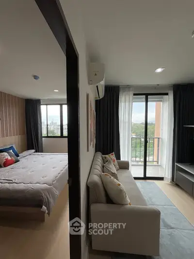 Modern apartment with cozy living room and bedroom, featuring a balcony with a scenic view.
