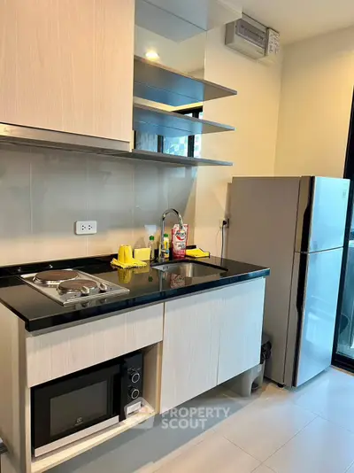 Modern kitchen with sleek cabinetry, built-in microwave, and stainless steel fridge in a stylish apartment.