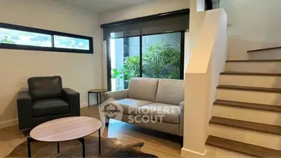 Modern living room with stylish furniture and large windows overlooking greenery.