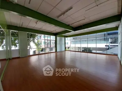 Spacious open room with large windows and wooden flooring, ideal for versatile use.