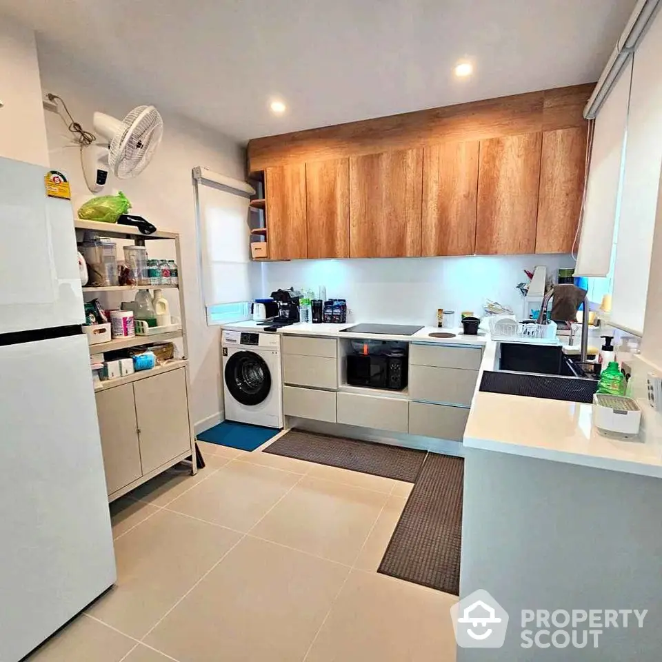 Modern kitchen with sleek cabinets, washing machine, and ample storage space.