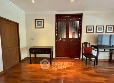 Elegant living room with wooden flooring and traditional decor, featuring a stylish desk and chair.