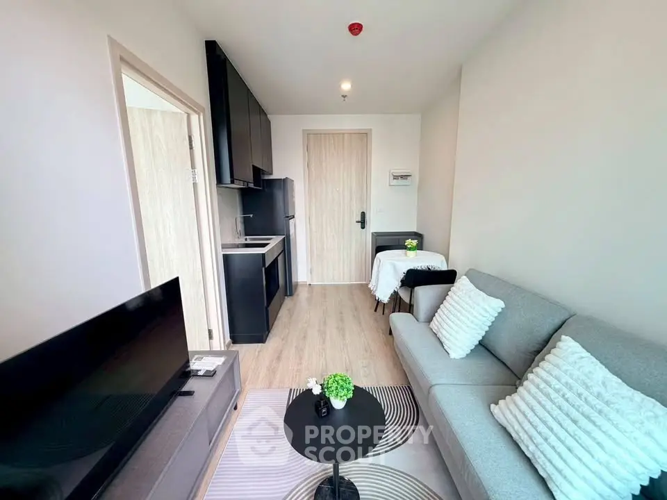 Modern living room with cozy sofa and sleek kitchen in open layout apartment.
