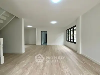 Spacious open-plan living area with wooden flooring and large windows for natural light.