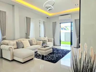 Luxurious modern living room with plush white sofa and elegant lighting, opening to a bright outdoor space.