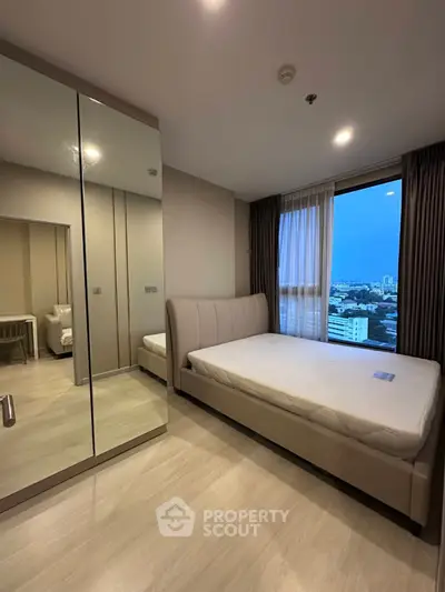 Modern bedroom with city view, featuring a large mirror wardrobe and elegant bed.