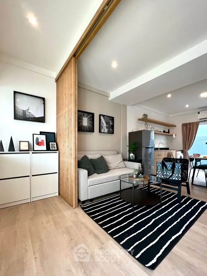 Modern living room with stylish decor and open kitchen layout, featuring sleek furniture and elegant lighting.