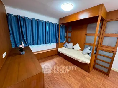 Cozy bedroom with wooden furnishings and blue curtains, featuring a built-in bed and ample storage.