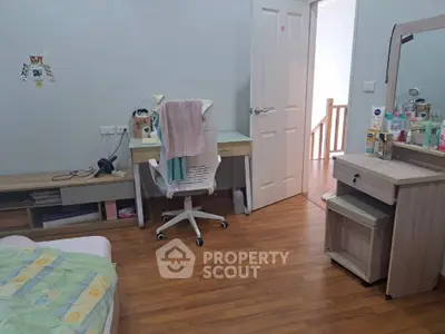 Cozy bedroom with wooden flooring, study desk, and vanity area.