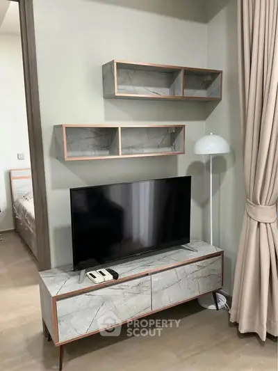 Modern living room with stylish TV stand and shelves, elegant floor lamp, and cozy curtains.