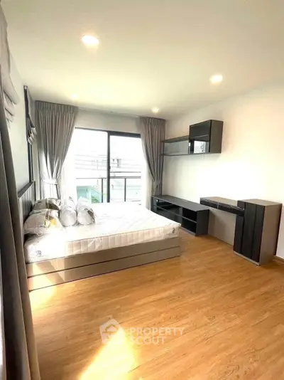 Spacious bedroom with modern furnishings and large window for natural light.